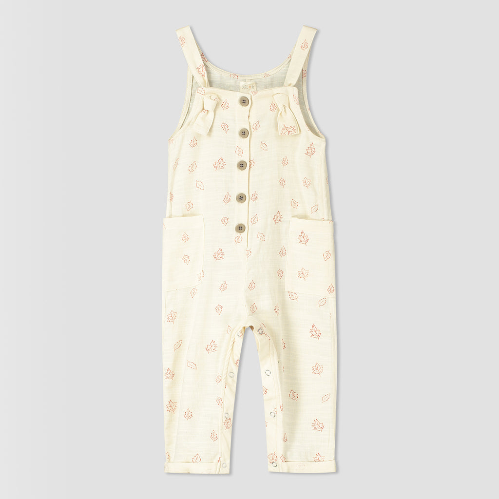 cream overalls with leaf all over print. knotted straps and buttons down the front bib. patch pockets at side 