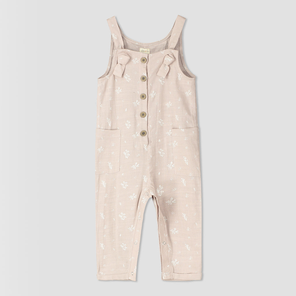 pink overalls with flower all over print. knotted straps and buttons down the front bib. patch pockets at side 
